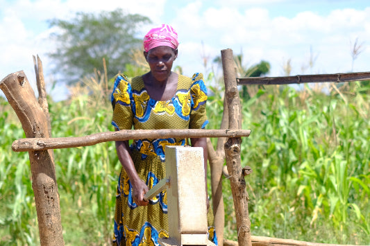 woman pumping water from well in colourful dress