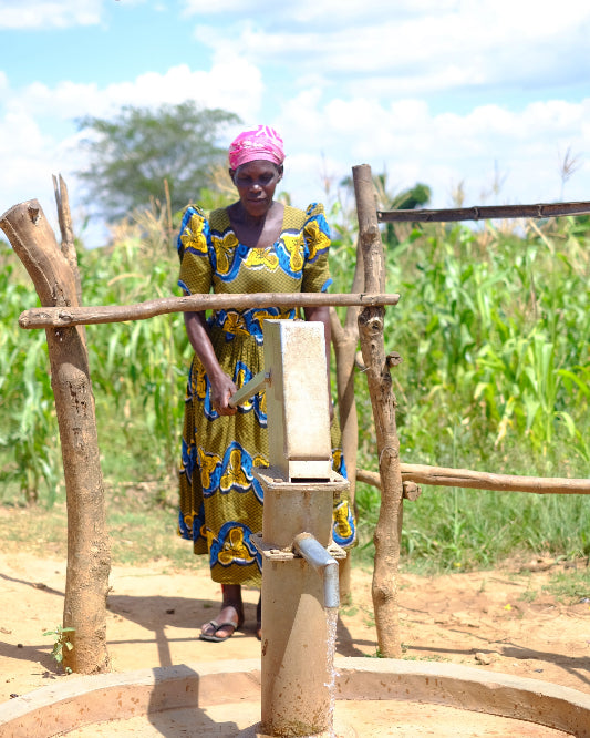 woman pumping water from well in colourful dress