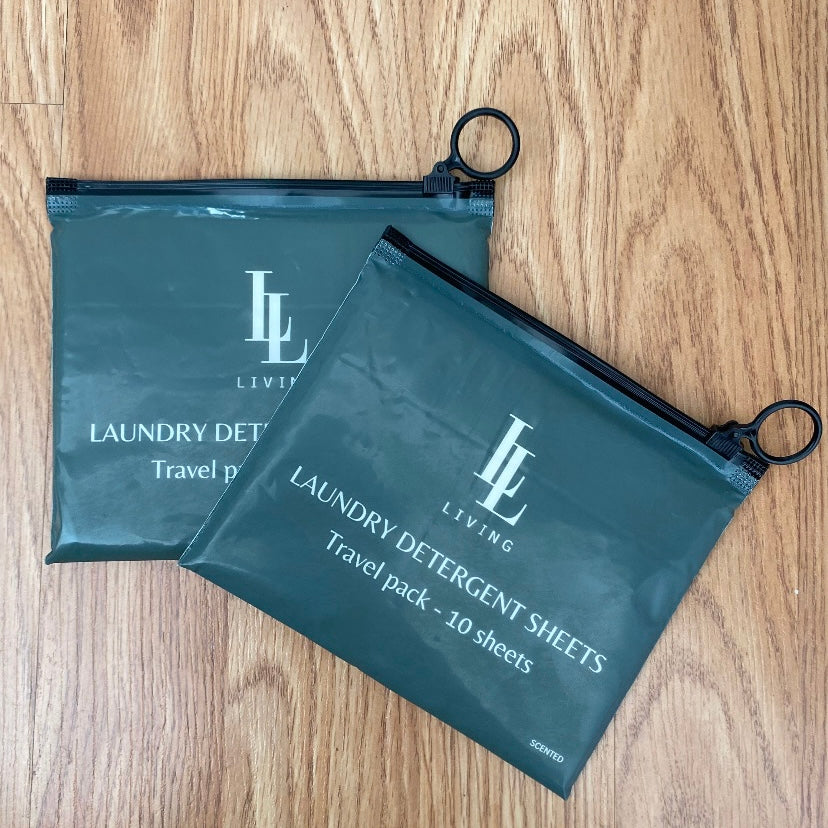 Two green bags with 'LL' branding travel size scented biodegradable detergent sheets on a wooden surface