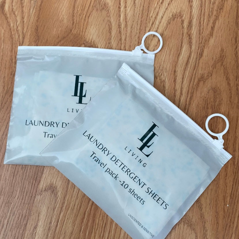 Two packages of unscented hypoallergenic travel size laundry detergent sheets on a wooden surface