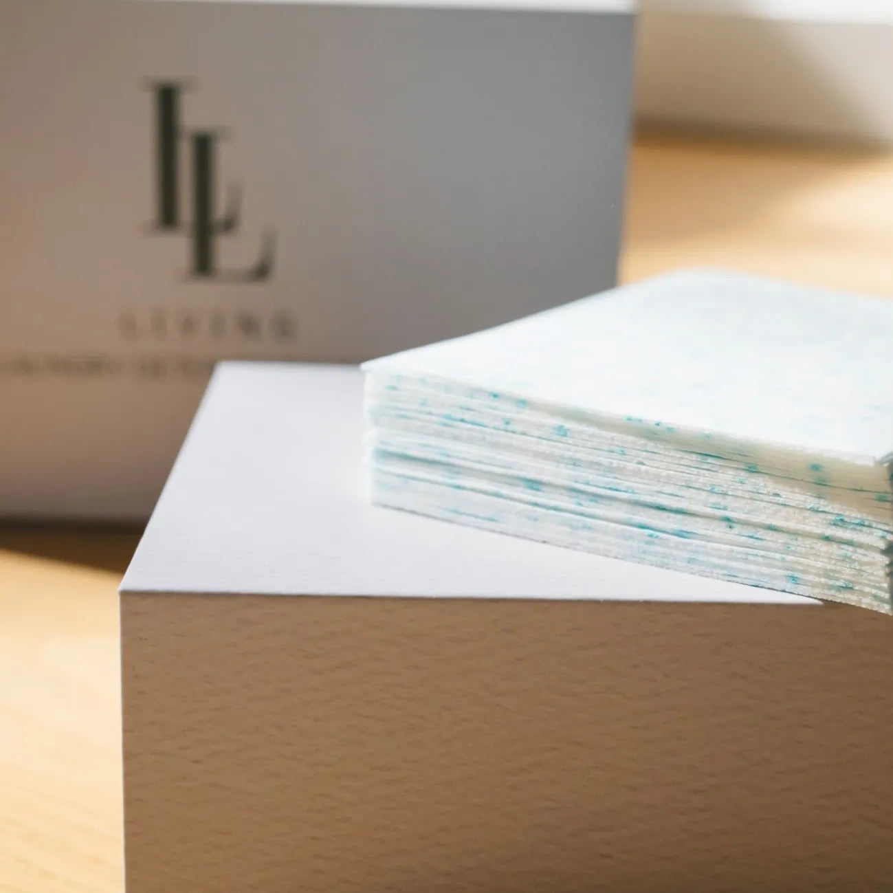 White box with a stack of papers on a wooden surface, with a blurred background