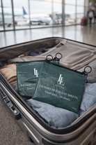 Two green laundry detergent packs in an open suitcase at an airport.