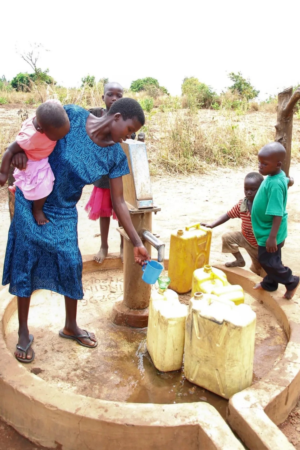 Woman and children at a water well with jerry cans