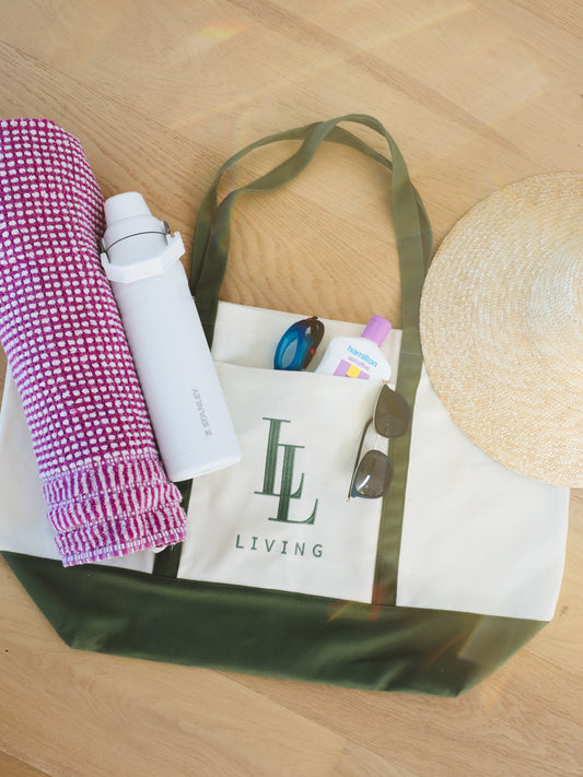 green tote laid flat with towel, drink bottle, sunnies, goggles and hats