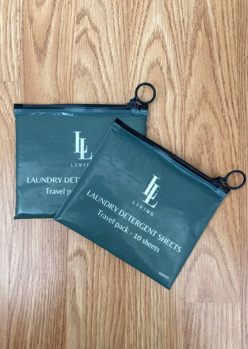 Two green bags with 'LL' branding travel size scented biodegradable detergent sheets on a wooden surface