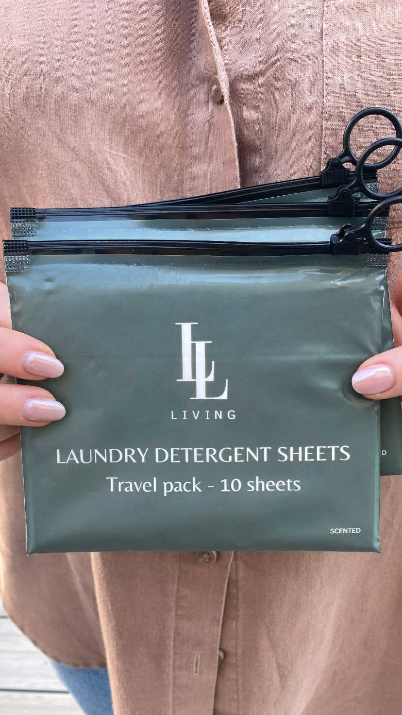 Package of laundry detergent sheets held by a person wearing a beige shirt.