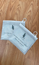 Two packages of unscented hypoallergenic travel size laundry detergent sheets on a wooden surface