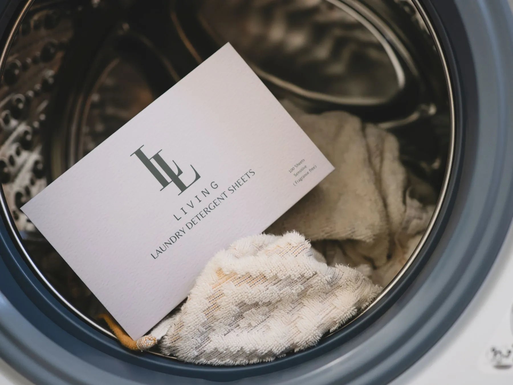 Living Laundry detergent sheets in a washing machine with brand card.