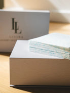 White box with a stack of papers on a wooden surface, with a blurred background